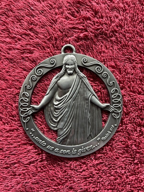 A silver medal with jesus in it