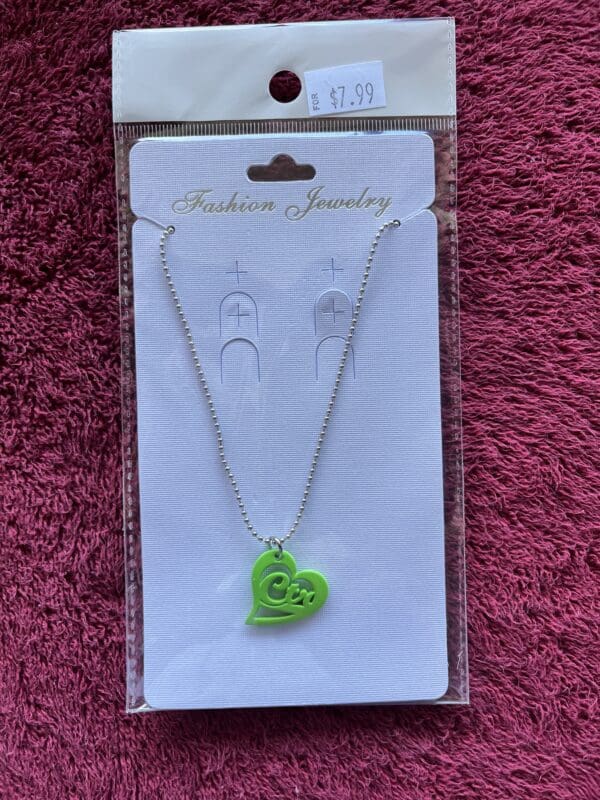 A green heart shaped necklace on a card.