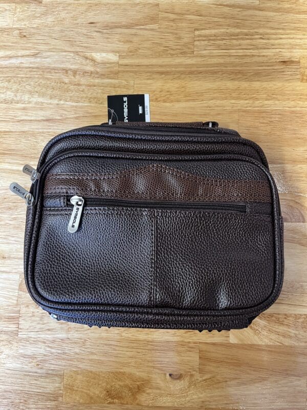 A brown leather bag sitting on top of a wooden floor.