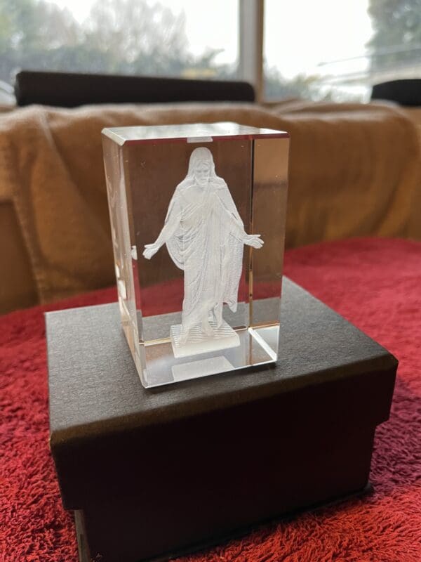 A glass cube with jesus on it sitting in front of a couch.